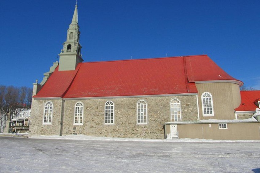 Een kerk met een rood dak en een hoge torenspits. 4
