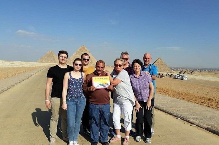Un gruppo di persone davanti alle piramidi, con cielo sereno. 4