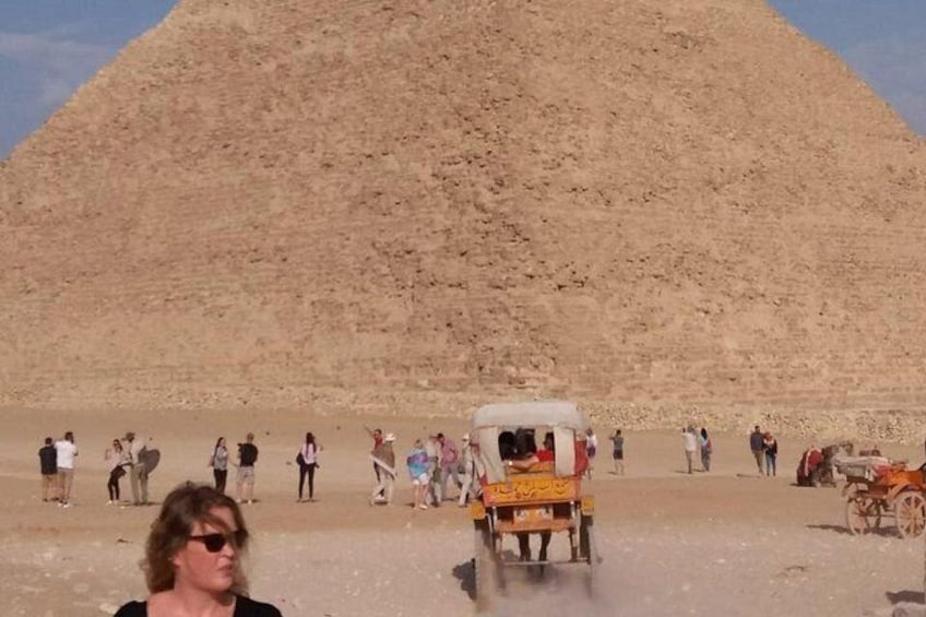 Una grande piramide, un gruppo di persone e un veicolo tradizionale. 2