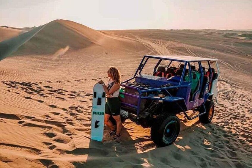 Et ørkenlandskab med sandklitter, og en dune buggy parkeret i sandet. 3
