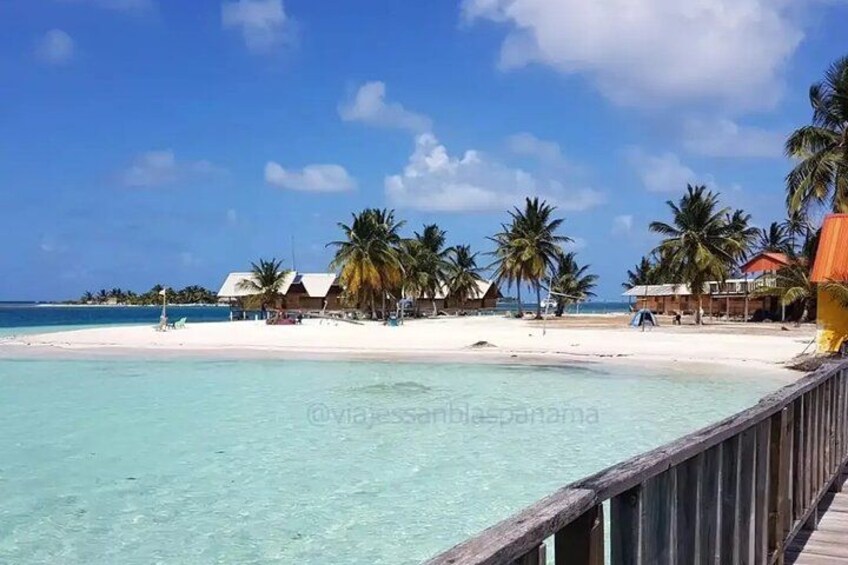 A beach with clear turquoise water, palm trees, and thatched-roof huts. 4
