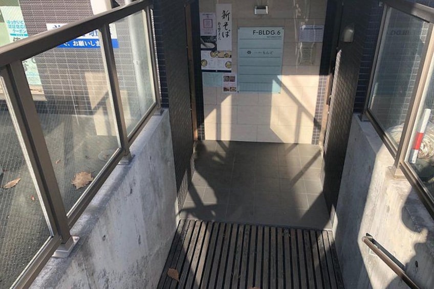 Eine Treppe führt zu einer Tür, an der ein Schild mit der Aufschrift 'F-BLDG.6' angebracht ist. 3