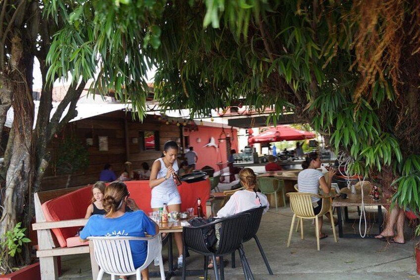 Un café en plein air avec des tables et des chaises, entouré d’arbres. 2