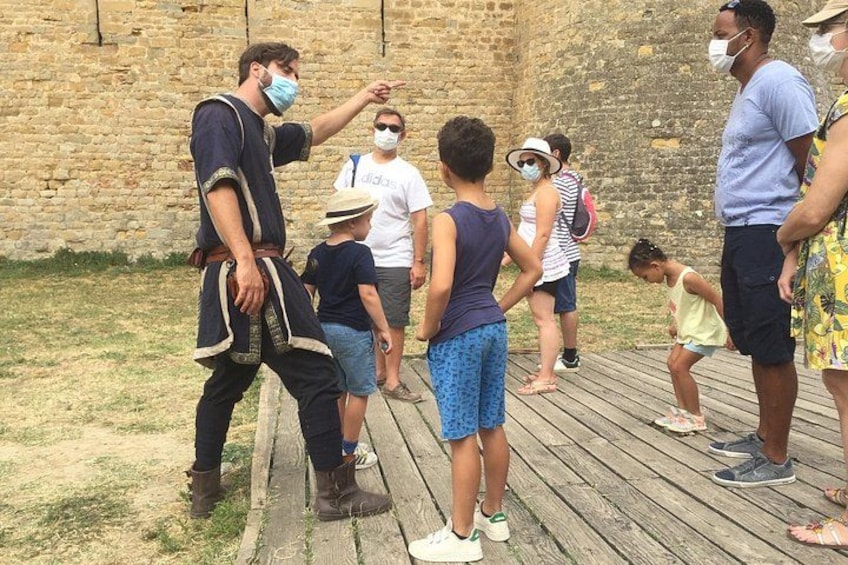 Un grupo de personas en una terraza de madera cerca de un muro de ladrillo. 1