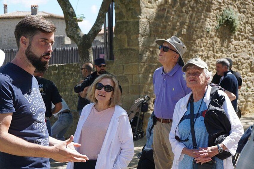 A group of people walking outdoors, with stone walls and a clear sky in the background. 3