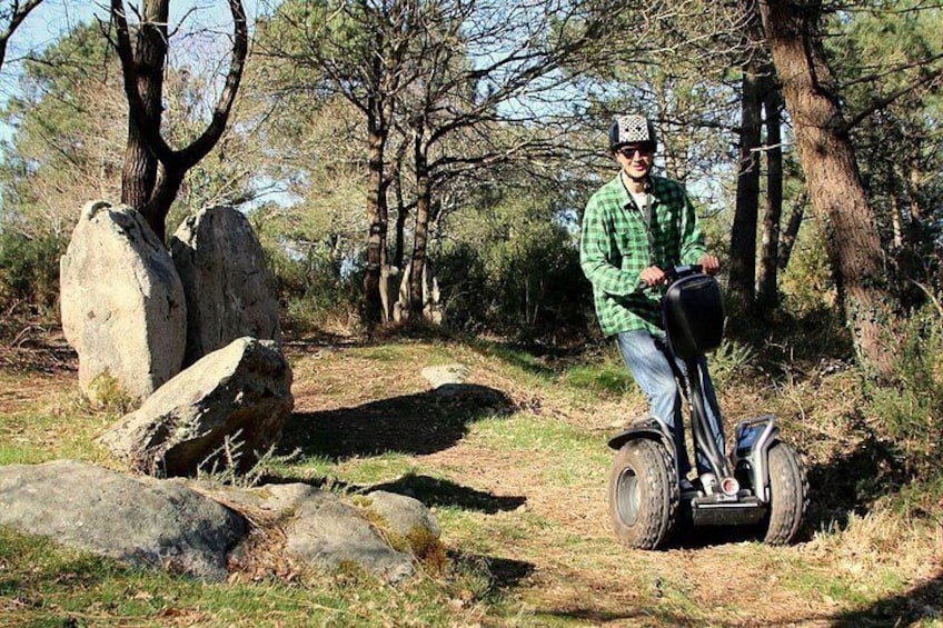 A person riding a Segway on a rocky path surrounded by trees. 3