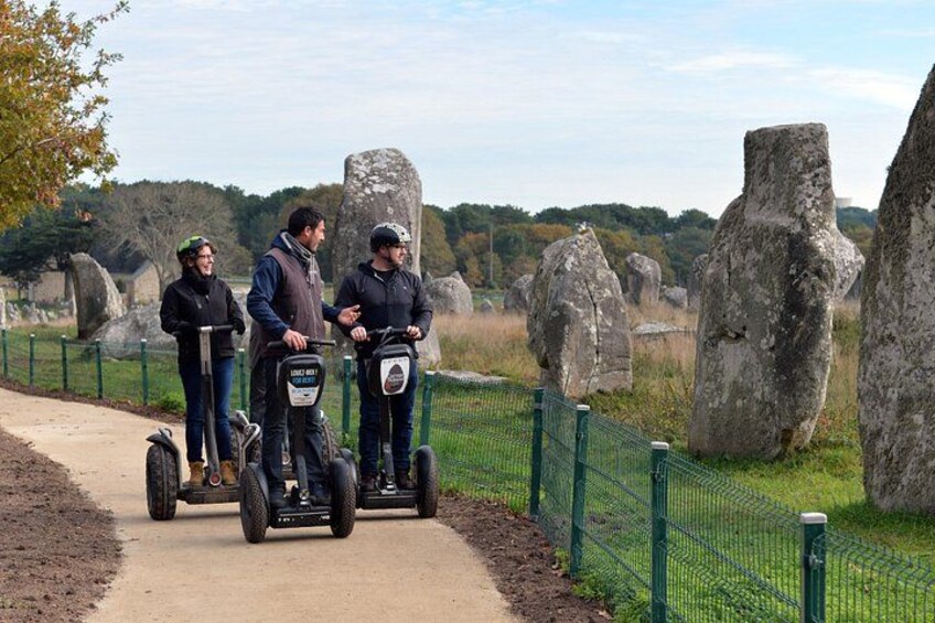 Three people on Segways near large stone structures. 2