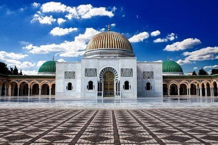 Una gran mezquita con dos cúpulas verdes, una cúpula central y un patio con baldosas estampadas. 3