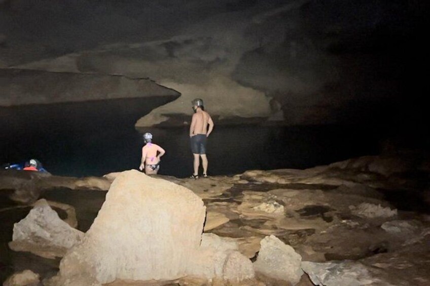 Una grotta con terreno roccioso e una persona in piedi su una sporgenza. 3