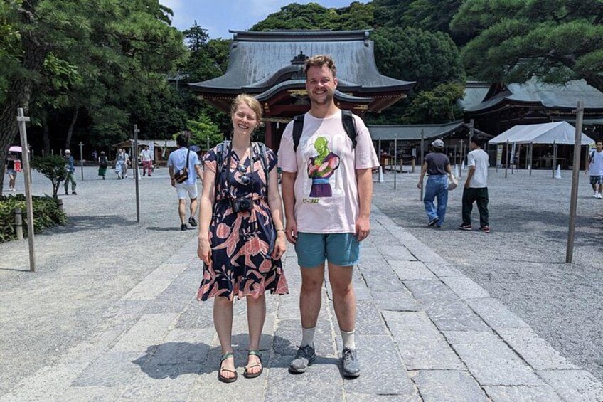 Twee personen staan voor een traditioneel Japans gebouw met een gebogen dak. 1