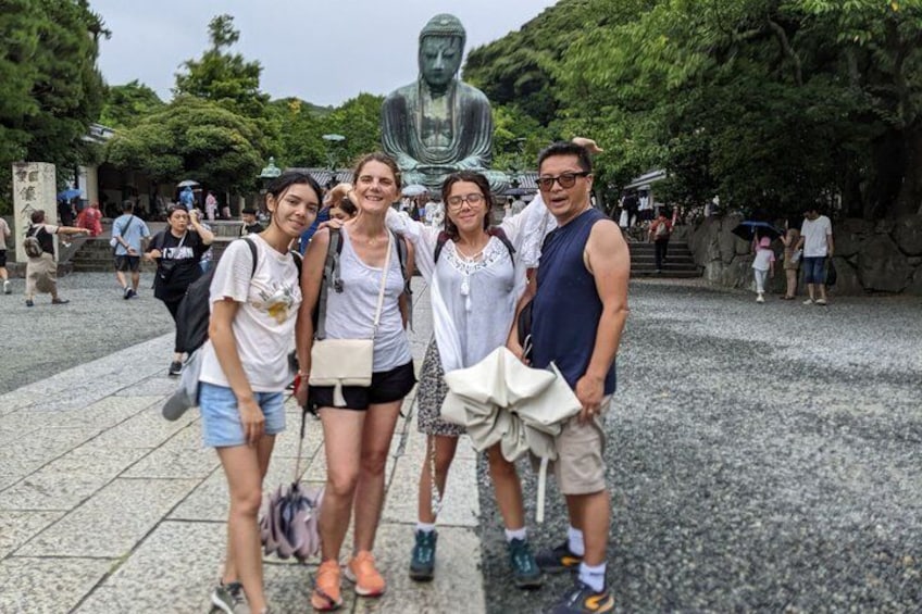 Eine Gruppe von Menschen posiert vor einer großen Buddha-Statue auf einem öffentlichen Platz. 1