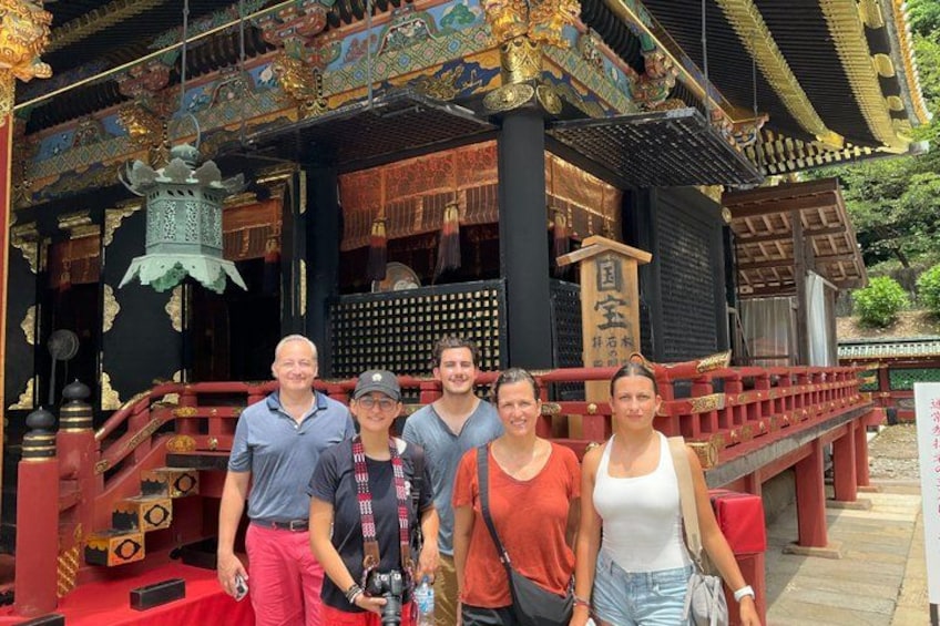 A group of people in front of a traditional temple with ornate architecture and a red bridge. 4