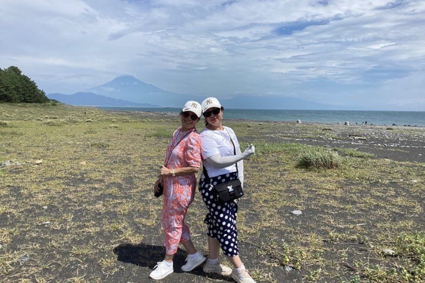 Two people standing on a beach with a mountain in the background. 3