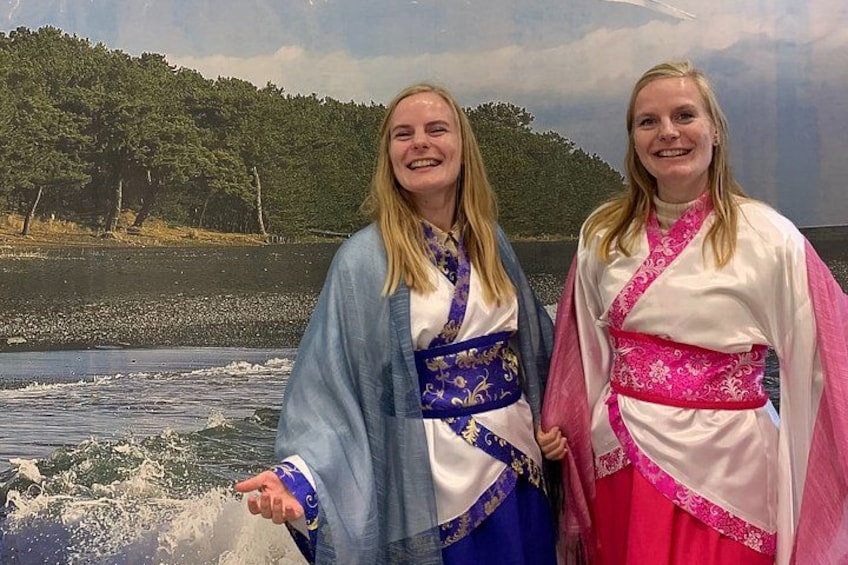 Two individuals in traditional attire by a lake with waves. 3
