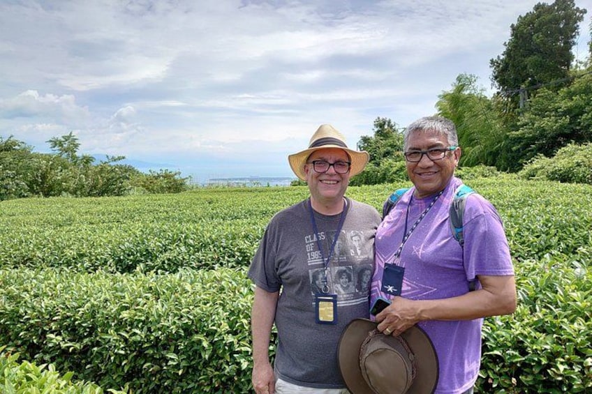 Two people standing in a field of green plants, one holding a hat. 4
