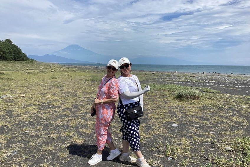 Two people standing on a beach with a mountain in the background. 4