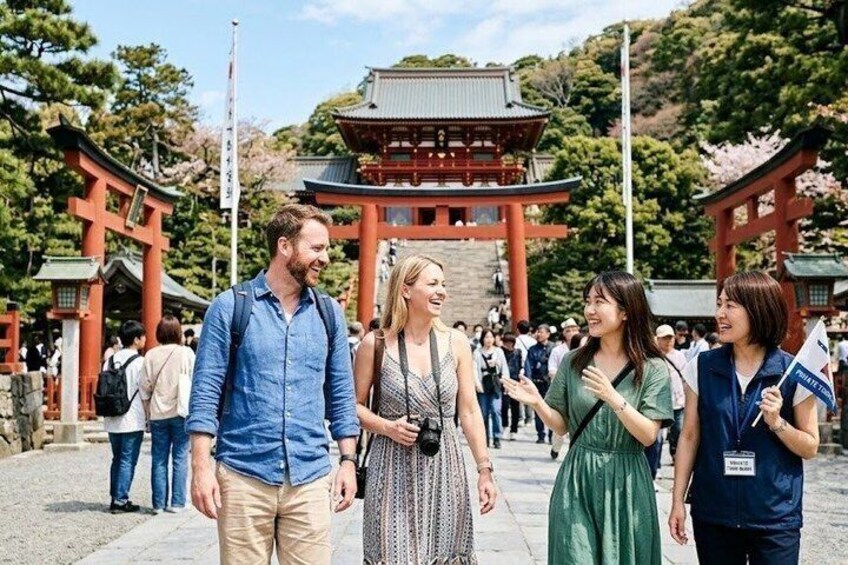 En grupp människor vid en traditionell japansk torii-port, med ett tempel i bakgrunden. 1