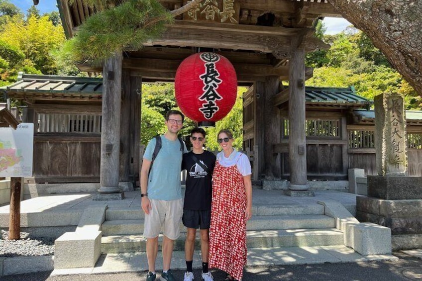 Tre personer står under en traditionell japansk byggnad med en röd lykta. 2
