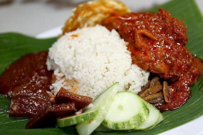 A plate of food with rice, meat, and cucumber slices on a banana leaf. 1