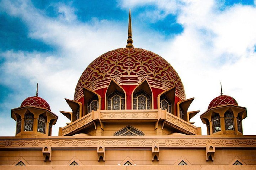 A large mosque with a prominent dome and two smaller domes, intricate architectural details, and a clear sky. 5