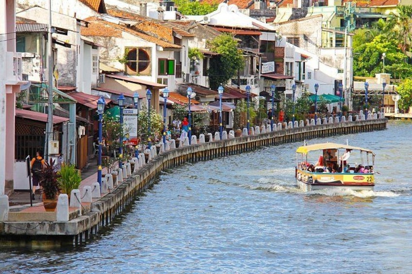 Un canal étroit bordé d’immeubles, un bateau transportant des passagers et une promenade piétonne. 4