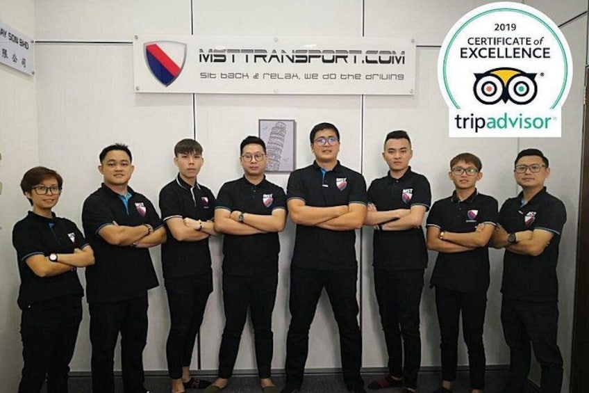 A group of people in black uniforms with crossed arms, standing in front of a wall with logos and a TripAdvisor certificate. 4