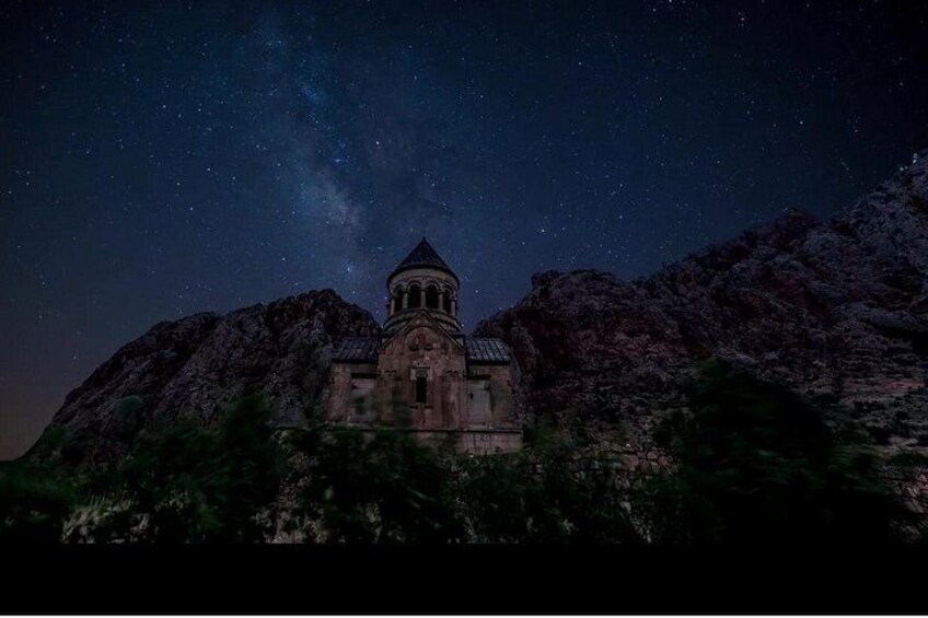 Una montaña con una iglesia en su cima bajo un cielo estrellado. 2