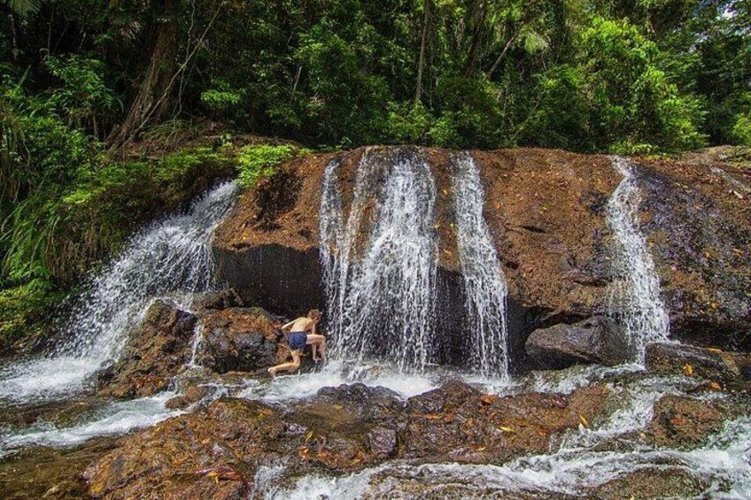 A waterfall with multiple streams cascading over rocks, surrounded by lush greenery. 2