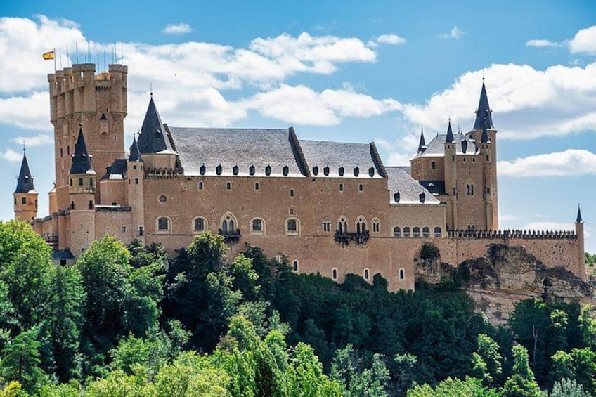 A large castle with multiple towers and a prominent central tower, surrounded by lush greenery. 2