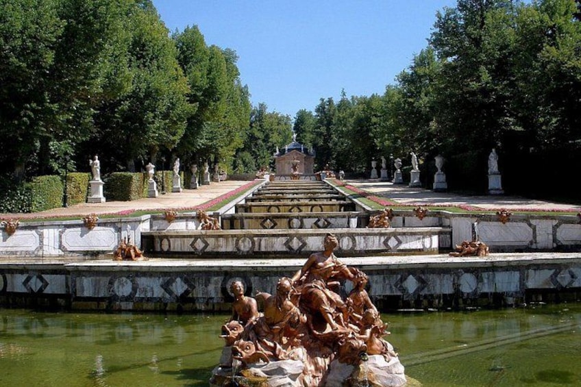 A landscaped garden with a central fountain, statues, and a clear sky. 4