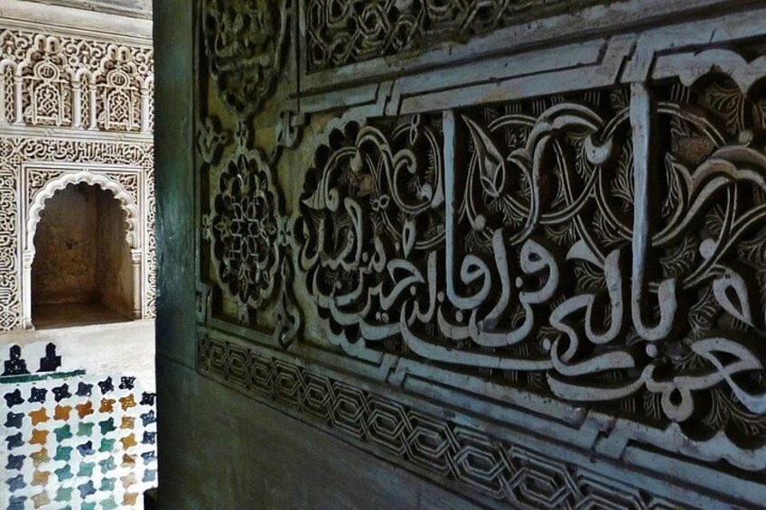 Intricate Arabic calligraphy on a wall, a detailed archway, and a patterned floor. 2