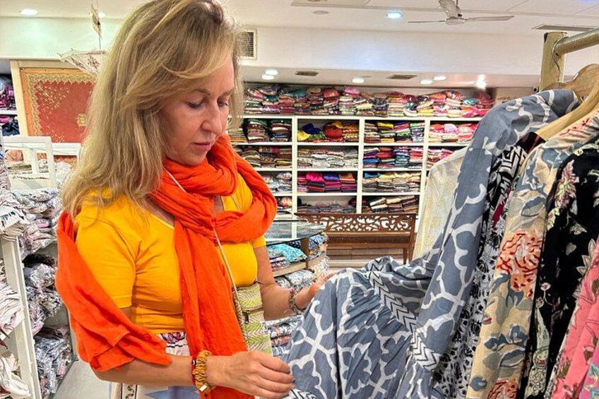 Iemand bekijkt patroonstof in een winkel, met planken vol opgevouwen textiel op de achtergrond. 3