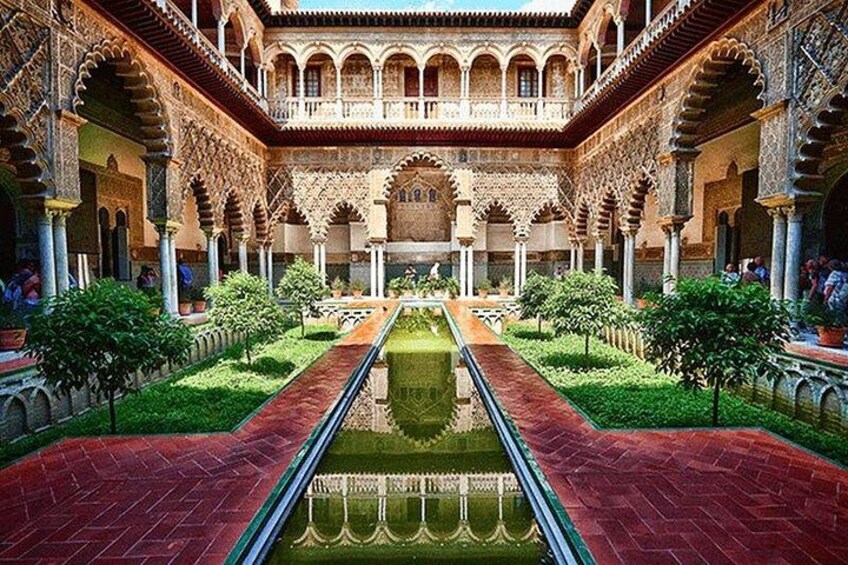 A courtyard with a central water channel, arches, and greenery. 4