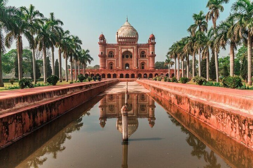 A large, symmetrical building with a central dome, surrounded by a reflective water body and palm trees. 2