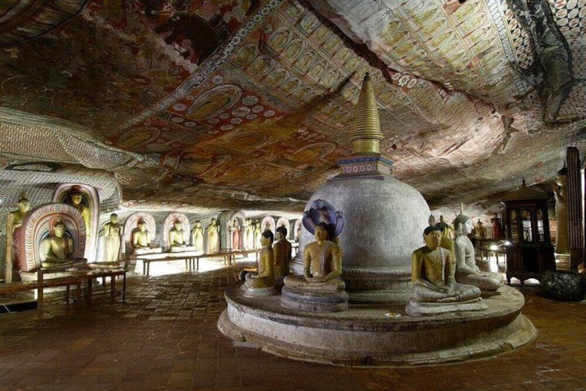 Interno di un tempio con statue di Buddha, una stupa centrale e decorazioni elaborate sul soffitto. 3