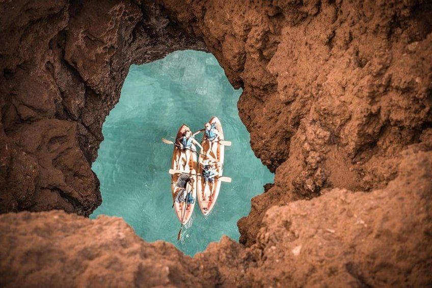 A group of people in a cave with a turquoise pool. 4