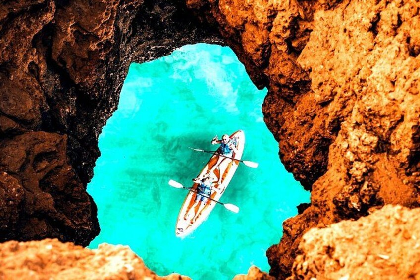 A kayak in a turquoise water body framed by rocky cliffs. 1