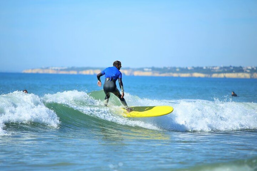 A surfer in a blue wetsuit riding a yellow surfboard on a wave. 1