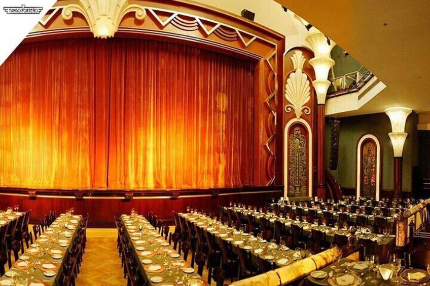 Une salle de spectacle où des rangées de tables sont disposées pour un événement. 4