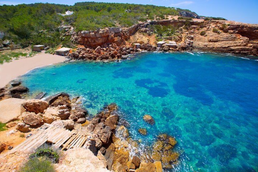 A coastal landscape with clear blue waters, rocky formations, and a sandy beach. 5