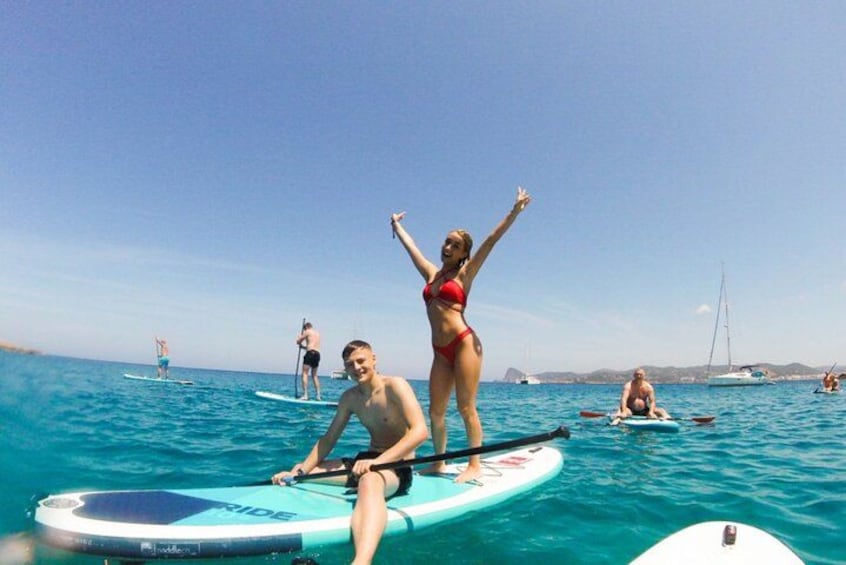 People on paddleboards in a body of water with boats in the background. 4