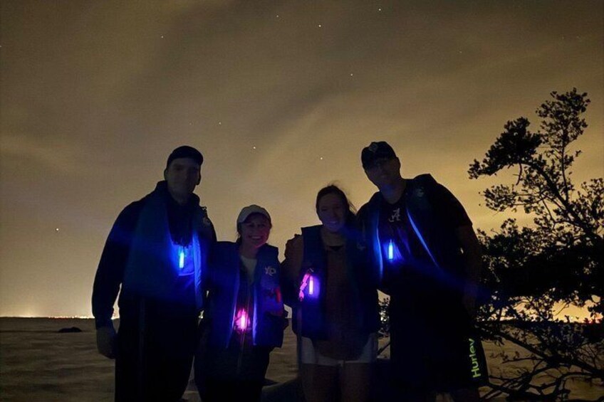 A group of people standing outdoors at night with blue lights. 5