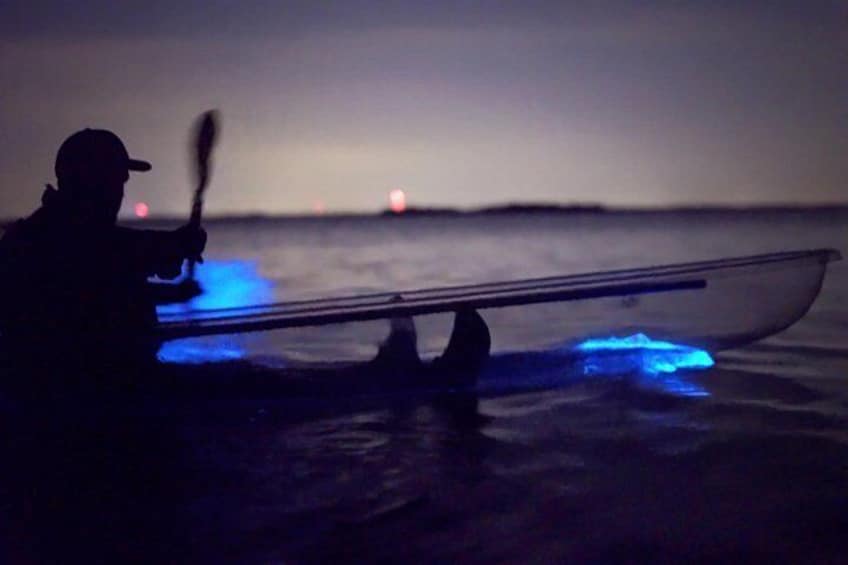 A person kayaking at night with blue lights on the kayak. 3