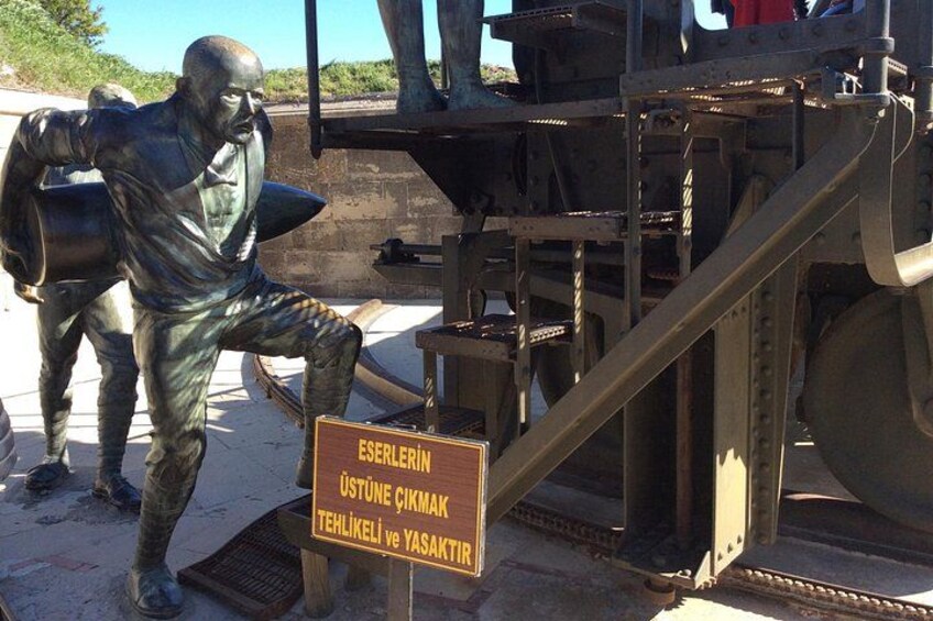 A statue of a man with a shovel, a sign with text, and a large mechanical structure. 2