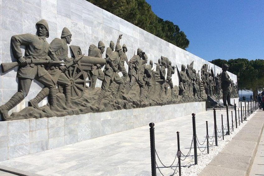 A large outdoor sculpture of soldiers in various poses, a paved walkway, and a clear sky. 3
