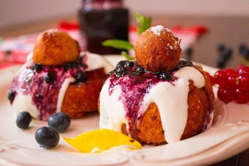 Two pastries topped with blueberries and white icing, accompanied by blueberries and a yellow fruit slice. 3