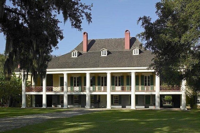 A large, colonial-style house with a symmetrical facade, multiple windows, and a central chimney. 1