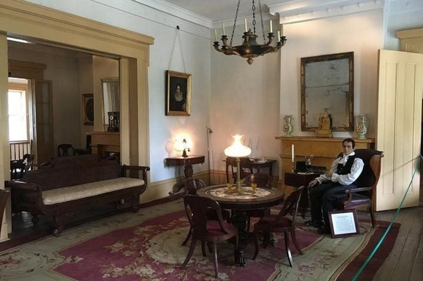 A room with a round table, chairs, a sofa, a chandelier, and a fireplace. 4