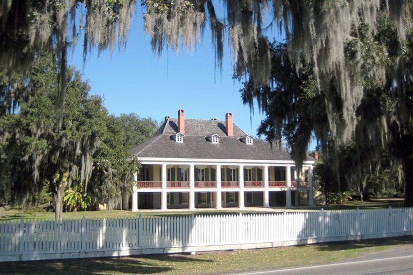 A large house with a white picket fence, surrounded by trees and greenery. 3