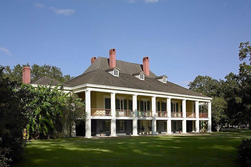 A large, two-story house with a wrap-around porch, surrounded by a well-maintained lawn and trees. 3